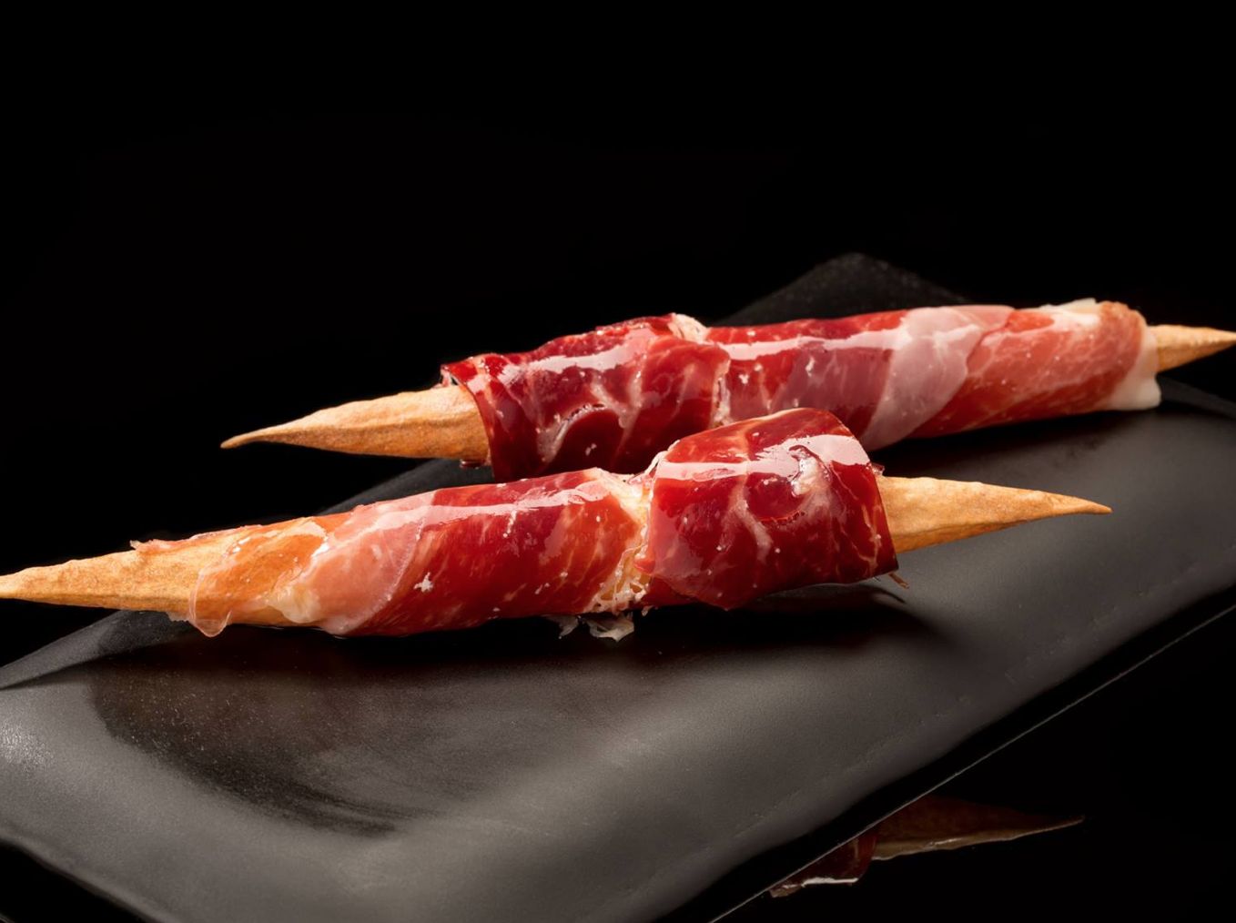 Dos bocados de jamón premium sobre pizarra